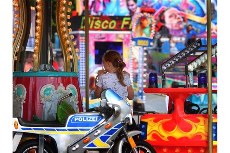 Ein Mädchen fährt auf dem Festplatz des Welfenfestes in einem Kinderkarussell. Foto: Karl-Josef Hildenbrand/dpa