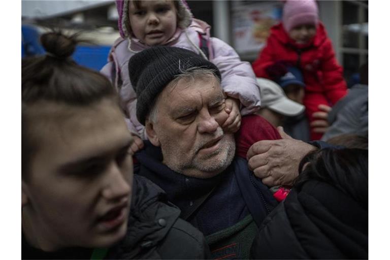 Ein Mädchen hält sich am Gesicht ihres Großvaters fest, während sie am Bahnhof von Kiew versuchen, in einen Zug nach Lwiw zu steigen. Foto: Emilio Morenatti/AP/dpa