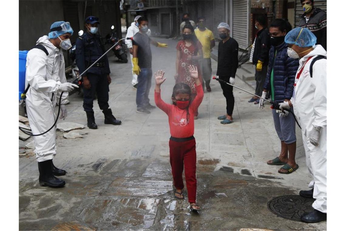 Möglicherweise 86 Millionen Kinder mehr in Armut Ein Mädchen in Nepal wird mit Desinfektionsmittel besprüht. Foto: Niranjan Shrestha/AP/dpa