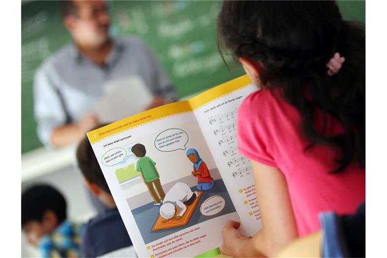 Ein Mädchen liest in einer Schule während des islamischen Religionsunterrichts in einem Schulbuch. Foto: Oliver Berg/Archivbild
