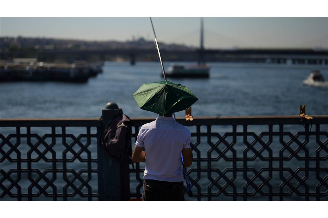 Bilder des Tages Ein Mann angelt an einem heißen Sommertag auf der Galata-Brücke in Istanbul.