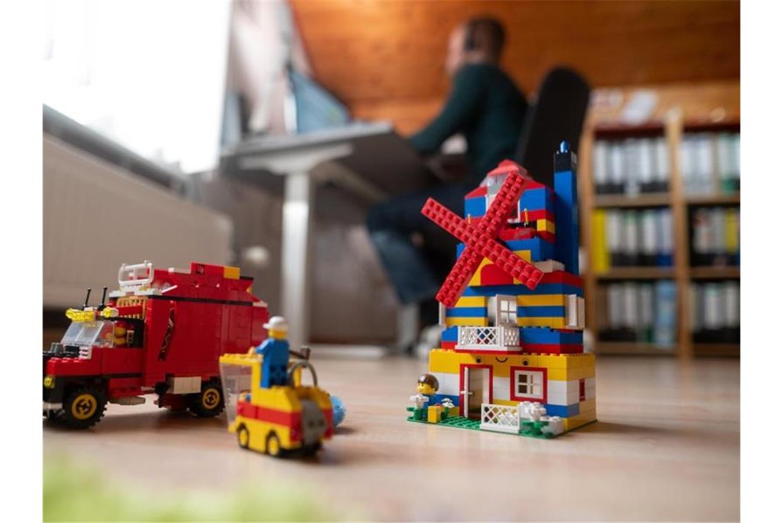 Ein Mann arbeitet im Homeoffice, während im Vordergrund Spielzeug seiner Kinder steht. Foto: Sebastian Gollnow/dpa