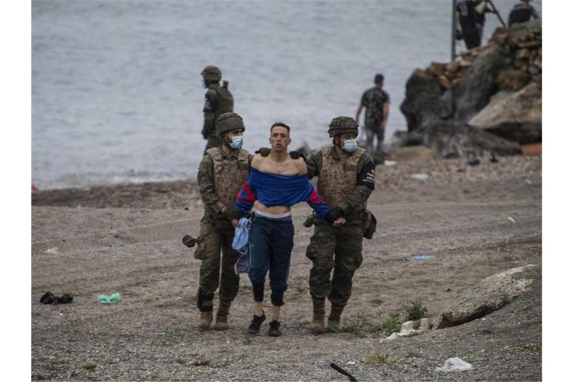 Marokko setzt Spanien mit Migranten in Ceuta unter Druck Ein Mann aus Marokko wird von Soldaten der spanischen Armee festgehalten. Foto: Javier Fergo/AP/dpa