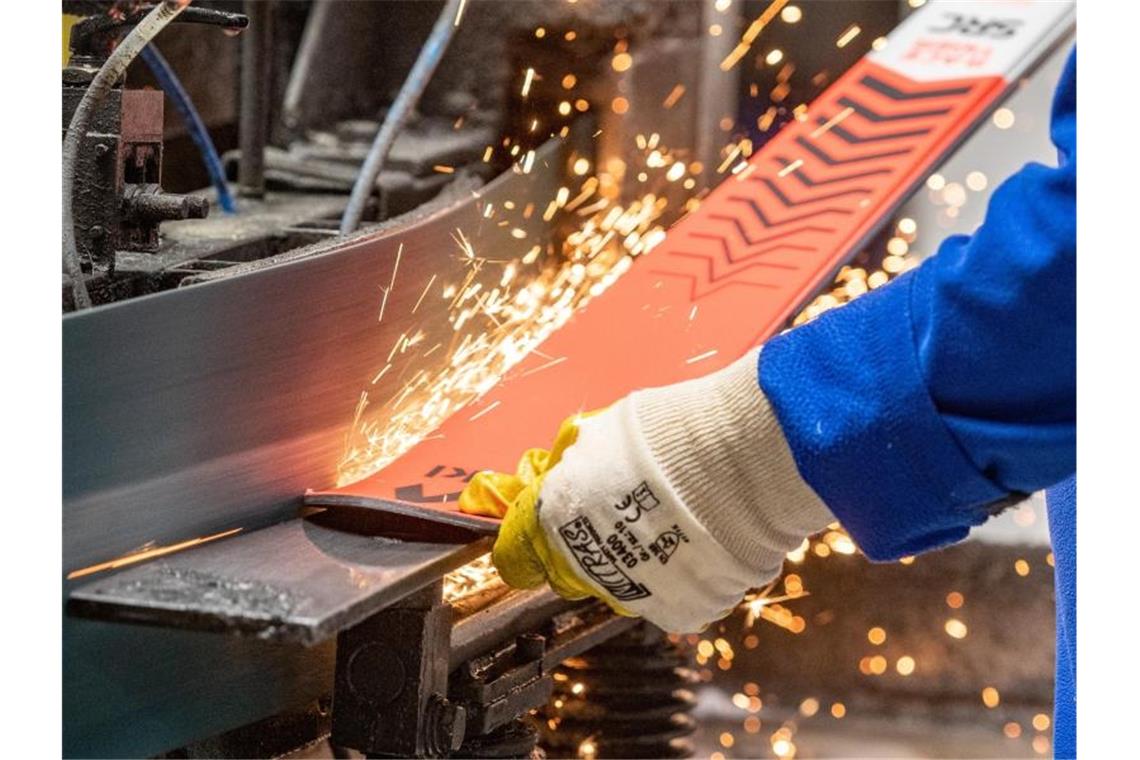 Ein Mann bearbeitet einen Ski in der Produktion des Skiherstellers Völkl. Foto: Armin Weigel/dpa