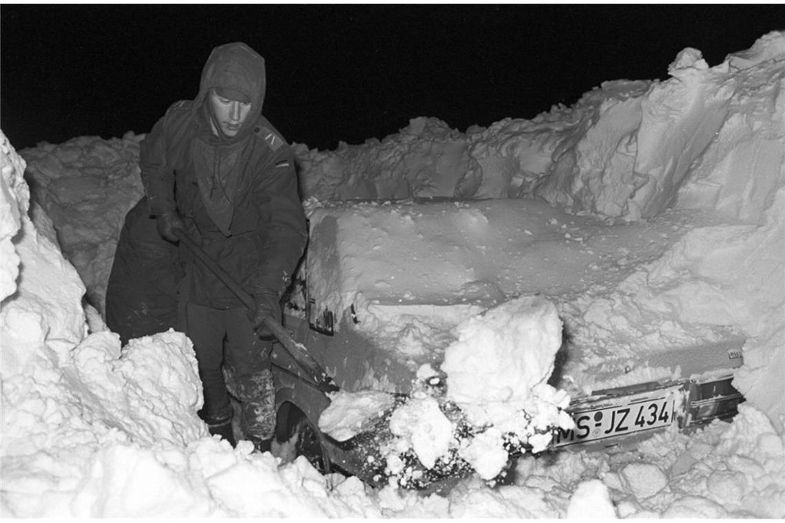 Ein Mann befreit in Hamburg sein Auto mit einer Schaufel von den Schneemassen.
