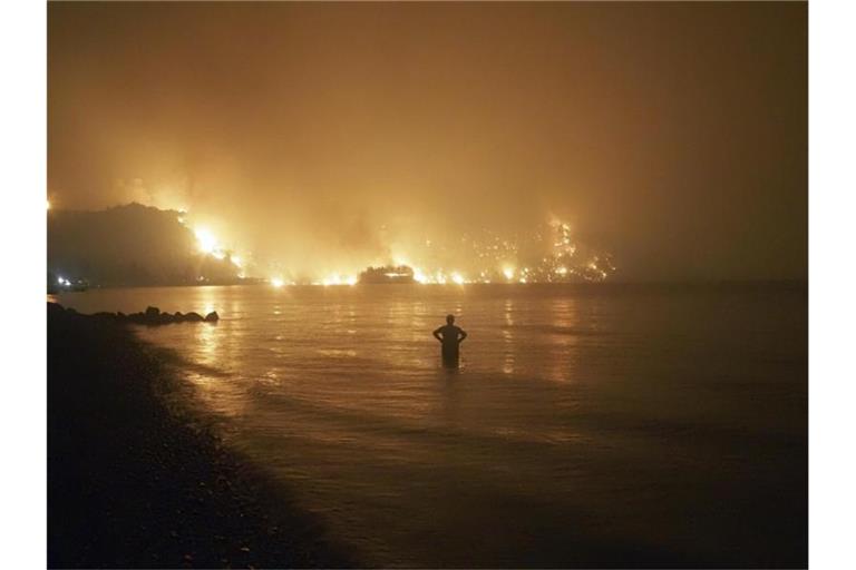 Ein Mann beobachtet im August 2021, wie sich Waldbrände dem Strand von Kochyli in der Nähe des Dorfes Limni auf der Insel Evia (Griechenland) nähern. Foto: Thodoris Nikolaou/AP/dpa