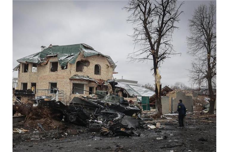 Ein Mann betrachtet die ausgebrannten Überreste russischer Militärfahrzeuge in Butscha. Foto: Serhii Nuzhnenko/AP/dpa