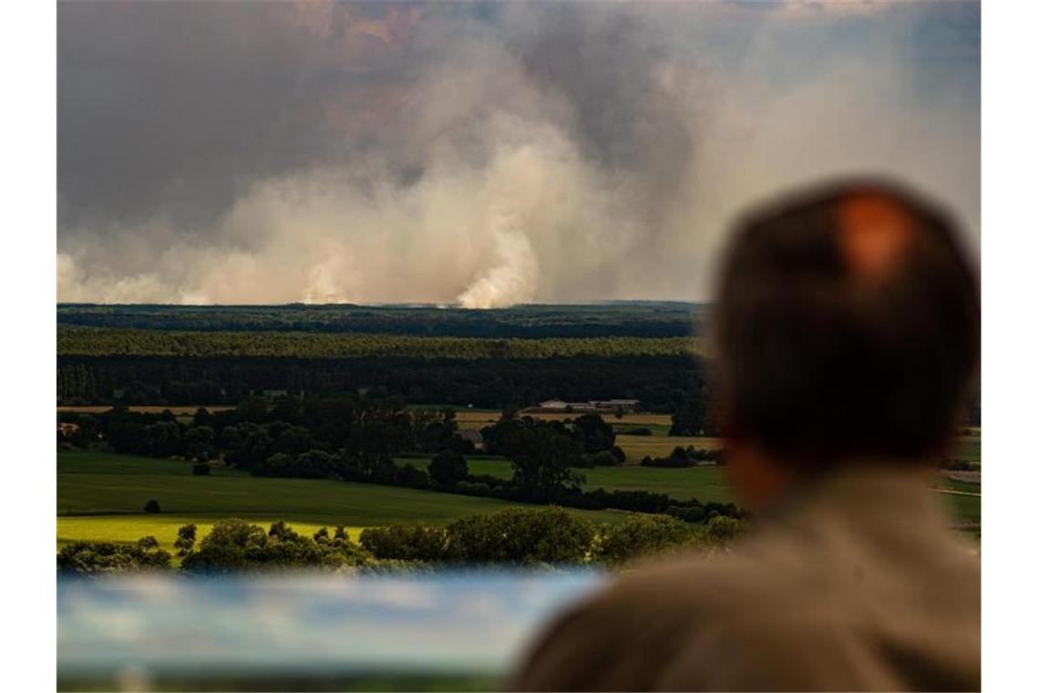 Erste Entspannung bei Waldbrand: Bewohner kehren zurück Ein Mann blickt von einem Aussichtsturm von Niedersachsen aus über die Elbe auf den Waldbrand bei Lübtheen in Mecklenburg-Vorpommern. Foto: Philipp Schulze