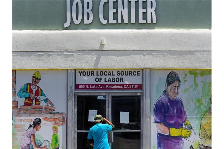 Ein Mann blickt während der Corona-Pandemie durch die geschlossenen Türen des örtlichen Jobcenters. Foto: Damian Dovarganes/AP/dpa
