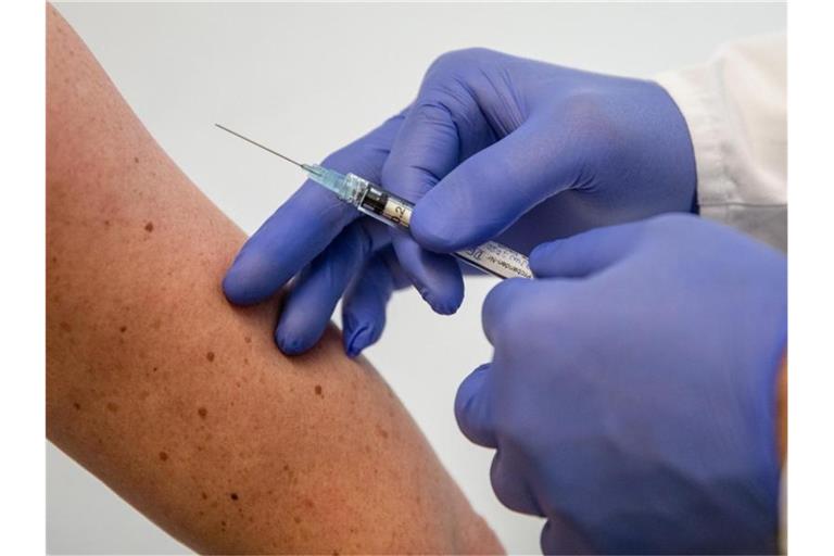 Ein Mann demonstriert im Institut für Tropenmedizin an der Uniklinik Tübingen, wie eine Frau geimpft wird. Foto: Christoph Schmidt/dpa/Illustration