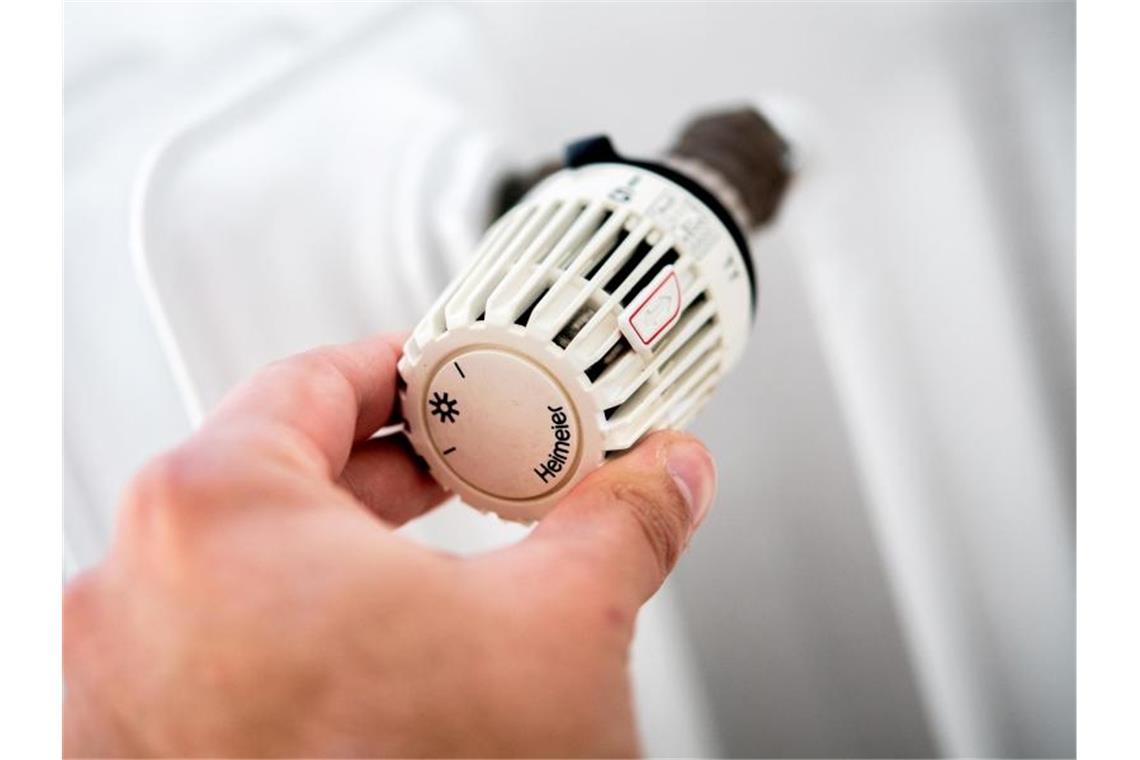 Ein Mann dreht am Thermostat einer Heizung. Foto: Hauke-Christian Dittrich/dpa