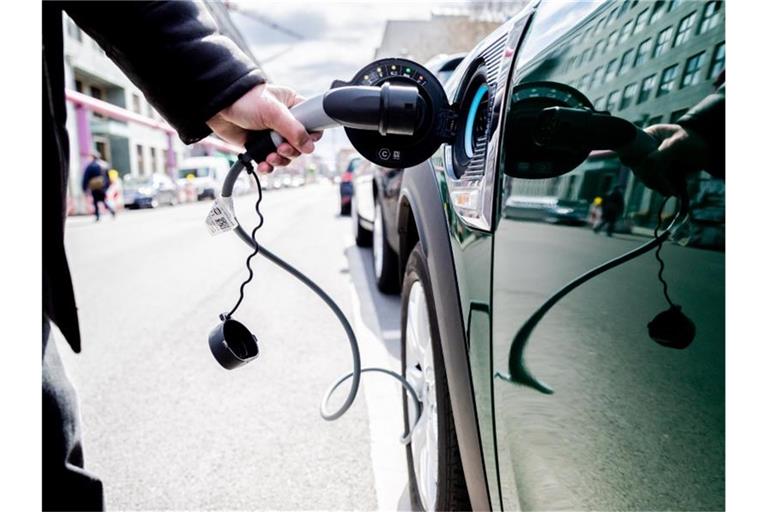 Ein Mann entfernt den Stecker an einem Auto mit Plug-in-Hybrid-Antrieb. Foto: Christoph Soeder/dpa/Symbolbild