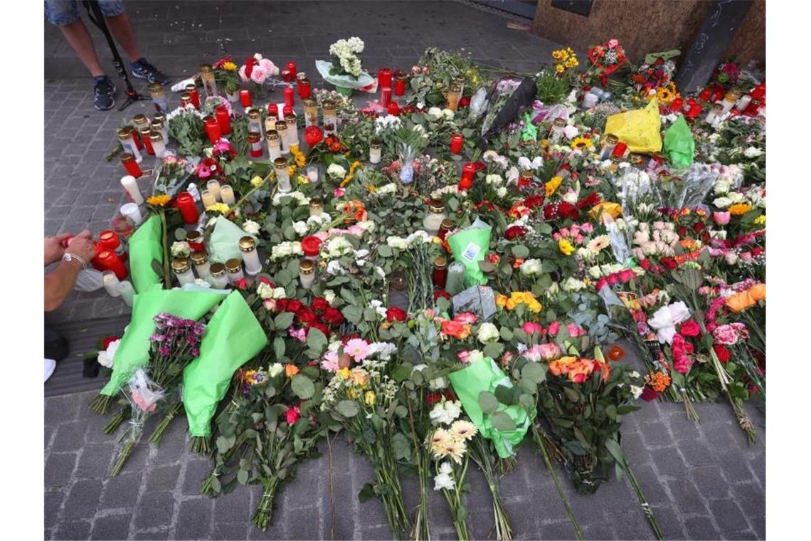 Messerangriff in Würzburg - Auf der Suche nach dem Motiv Ein Mann entzündet vor einem geschlossenen und abgesperrten Kaufhaus in der Innenstadt eine Kerze. Foto: Karl-Josef Hildenbrand/dpa