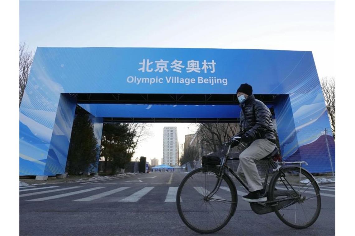Olympische Dörfer ohne Feier eröffnet - Politischer Streit Ein Mann fährt in der Nähe des Athletendorfs in der chinesischen Hauptstadt Peking Fahrrad. Foto: -/Kyodo/dpa