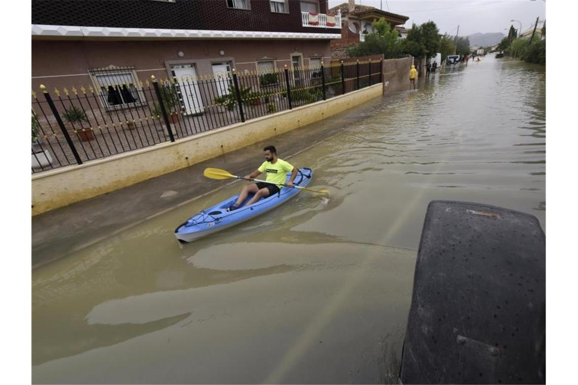 Ein Mann fährt in einem Kanu über eine überflutete Straße. Foto: Alfonso Duran/AP