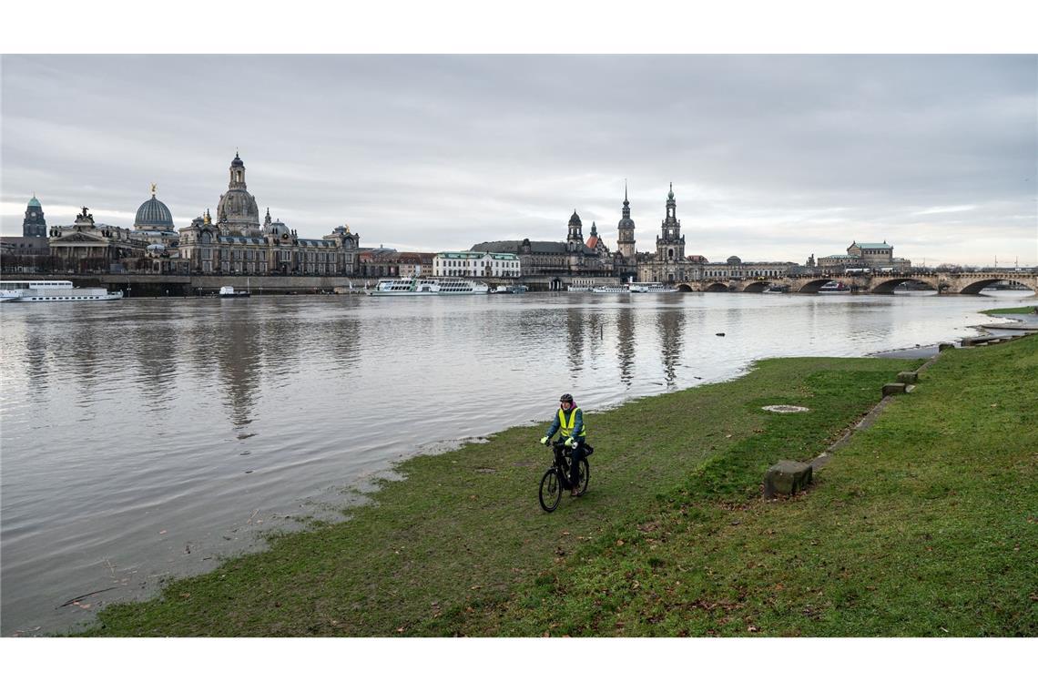 Ein Mann fährt mit seinem Fahrrad über die vom Hochwasser überfluteten Elbwiesen am Königsufer in Dresden entlang.