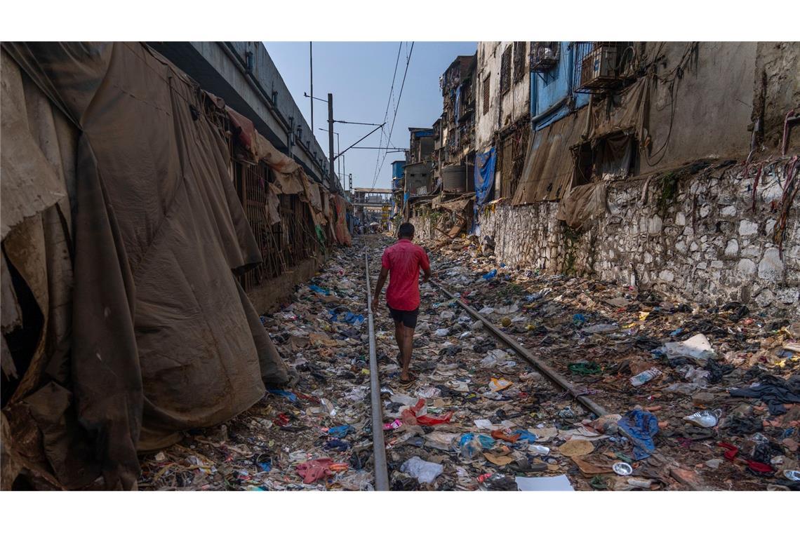 Ein Mann geht am Tag der Erde über ein mit Plastik und anderen Abfällen übersätes Bahngleis in Mumbai.