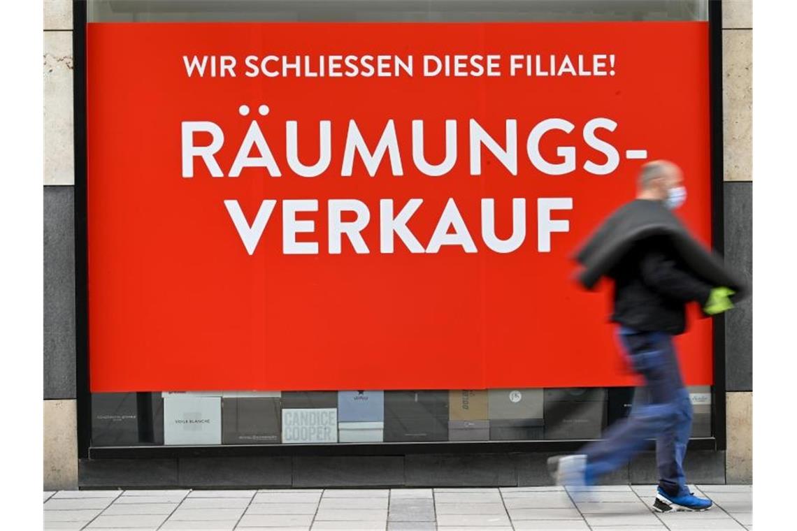 Ein Mann geht an einem Ladengeschäft in der Innenstadt von München vorbei, auf dessen Fenster „Wir schliessen diese Filiale! Räumungsverkauf“ steht. Foto: Peter Kneffel/dpa/Symbolbild