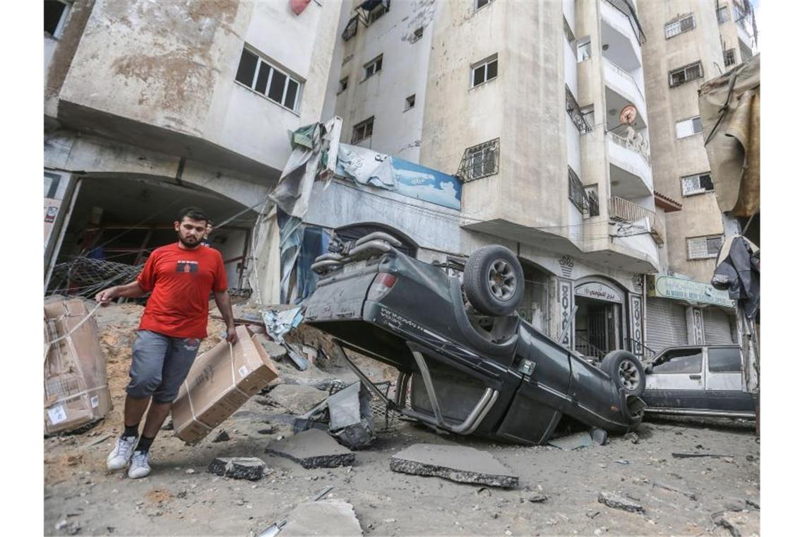 Keine Entspannung in Sicht - neue Angriffswelle in Israel Ein Mann geht an einem umgestürtzen Autowrack vor einem Wohnhaus, welches zuvor von israelischen Luftangriffen getroffen wurde, vorbei. Foto: Mohammed Talatene/dpa