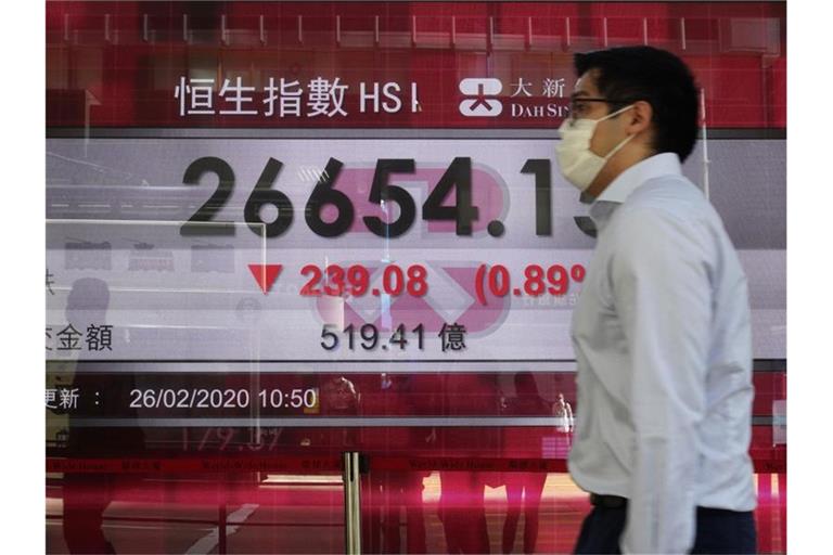 Ein Mann geht an einer Anzeigentafel der Hongkonger Börse vorbei. Wegen des Coronavirus rutschen auch Asiatische Aktien ab. Foto: Vincent Yu/AP/dpa