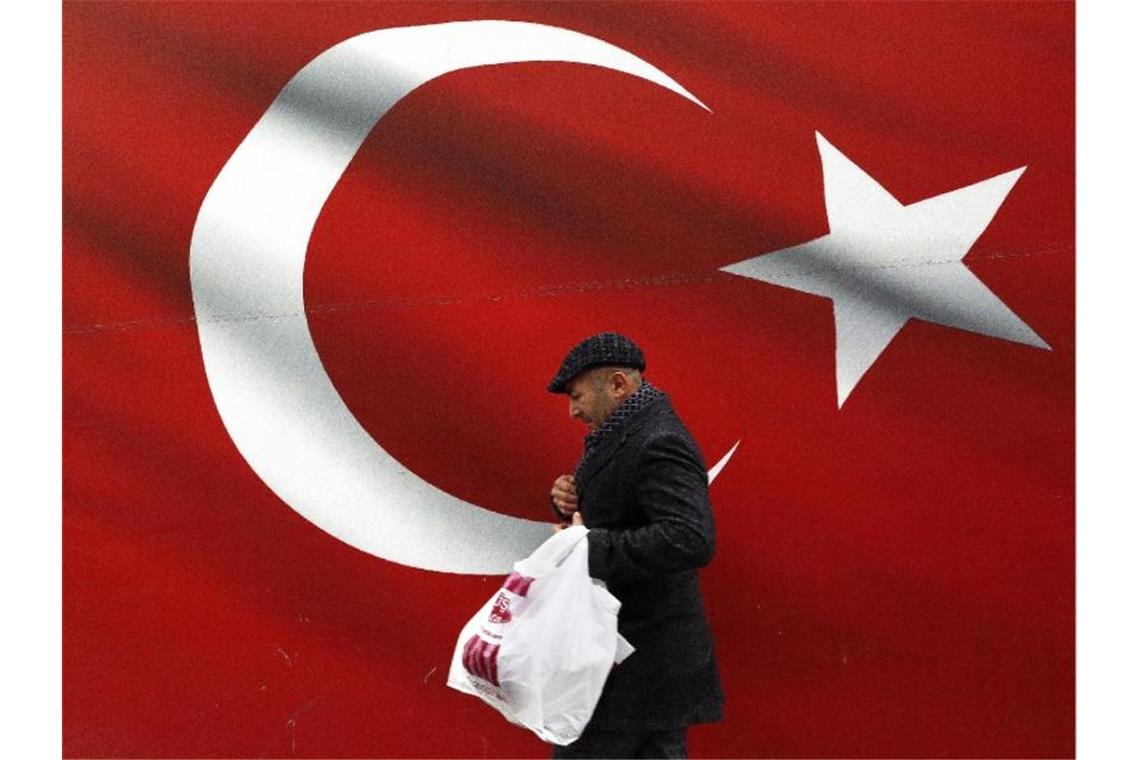 Ein Mann geht an einer türkischen Flagge vorbei. Foto: Ali Unal/AP