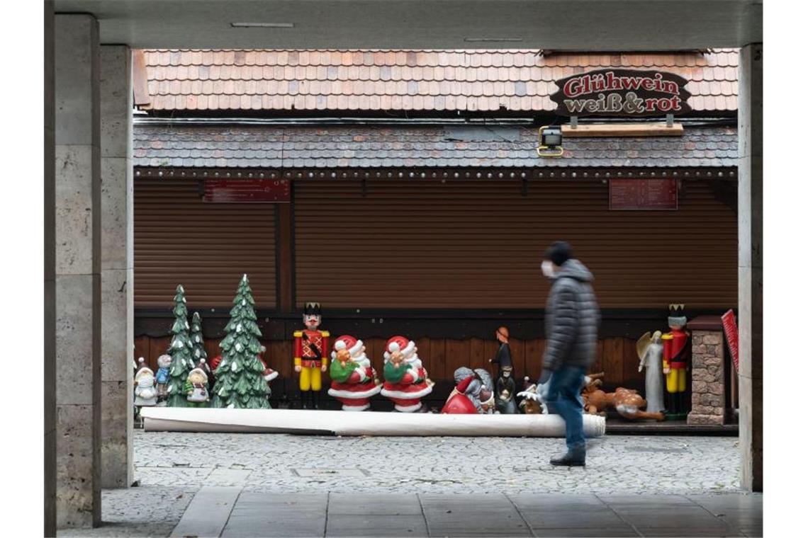Ein Mann geht an einer Weihnachtsmarktsbude vorbei. Foto: Marijan Murat/dpa