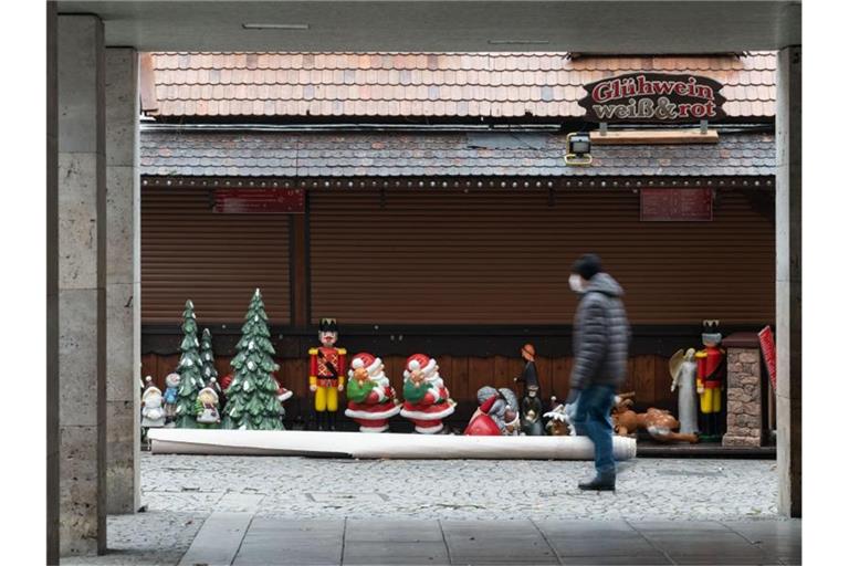 Ein Mann geht an einer Weihnachtsmarktsbude vorbei. Foto: Marijan Murat/dpa/Archivbild