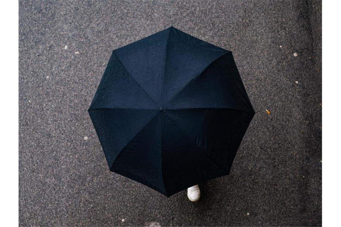 Regen und Ruhe am Feiertag: Viele Väter bleiben zuhause Ein Mann geht mit Regenschirm spazieren. Foto: Nicolas Armer/dpa/aktuell