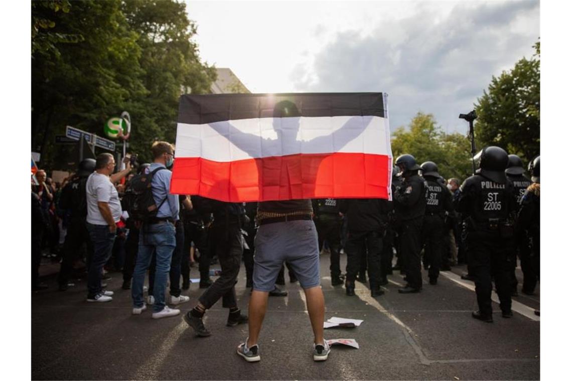 Ein Mann hält bei einem Protest gegen die Corona-Maßnahmen in Berlin eine Reichsflagge. Foto: Christoph Soeder/dpa