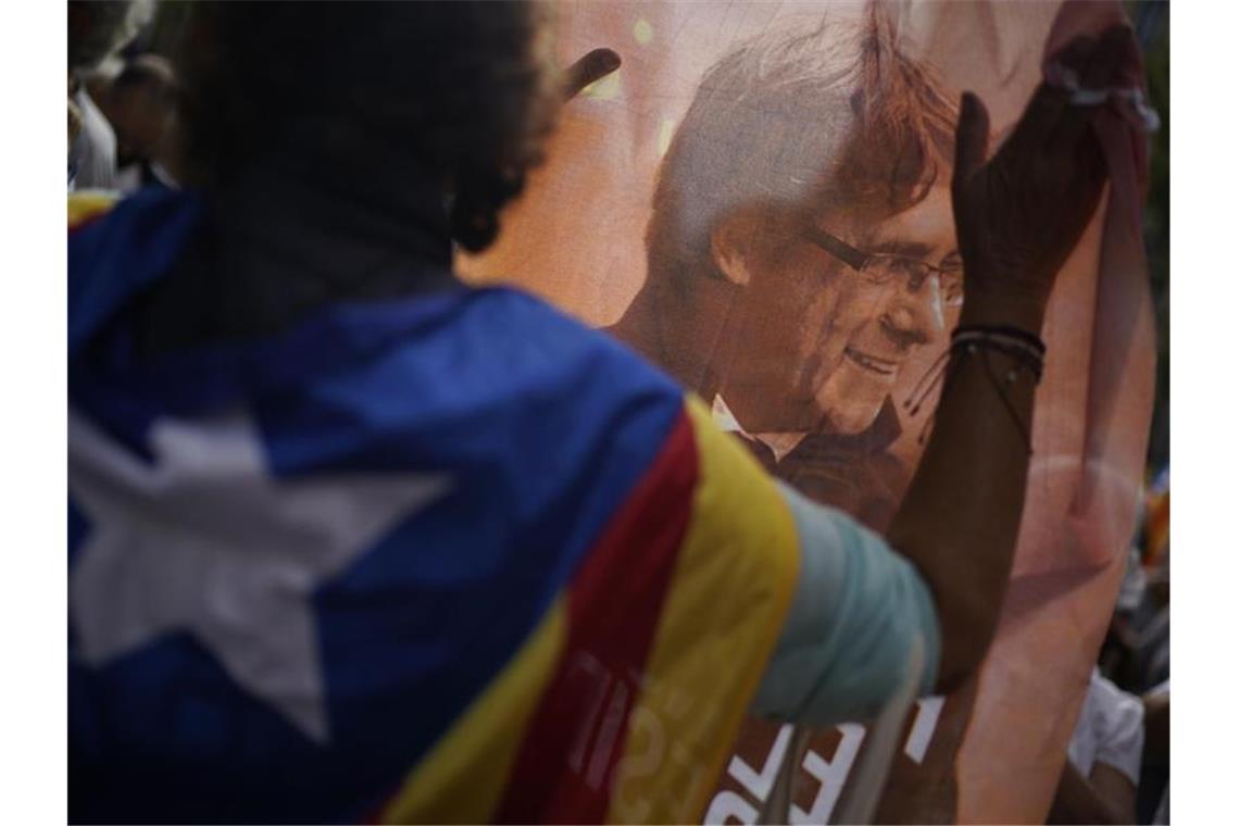 Ein Mann hält ein bedrucktes Tuch mit dem Bild des ehemaligen katalanischen Regierungschefs Puigdemont während eines Protests vor dem italienischen Konsulat in Barcelona. Foto: Joan Mateu/AP/dpa