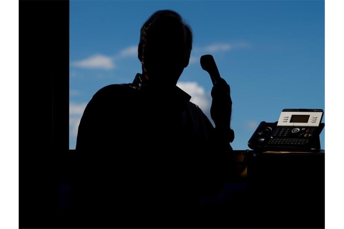 Ein Mann hält ein Telefon. Foto: Julian Stratenschulte/dpa/Illustration