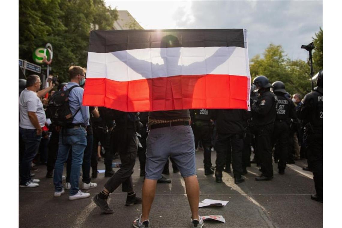 Ein Mann hält eine Reichsflagge bei einem Protest gegen die Corona-Maßnahmen vor der russischen Botschaft. Foto: Christoph Soeder/dpa