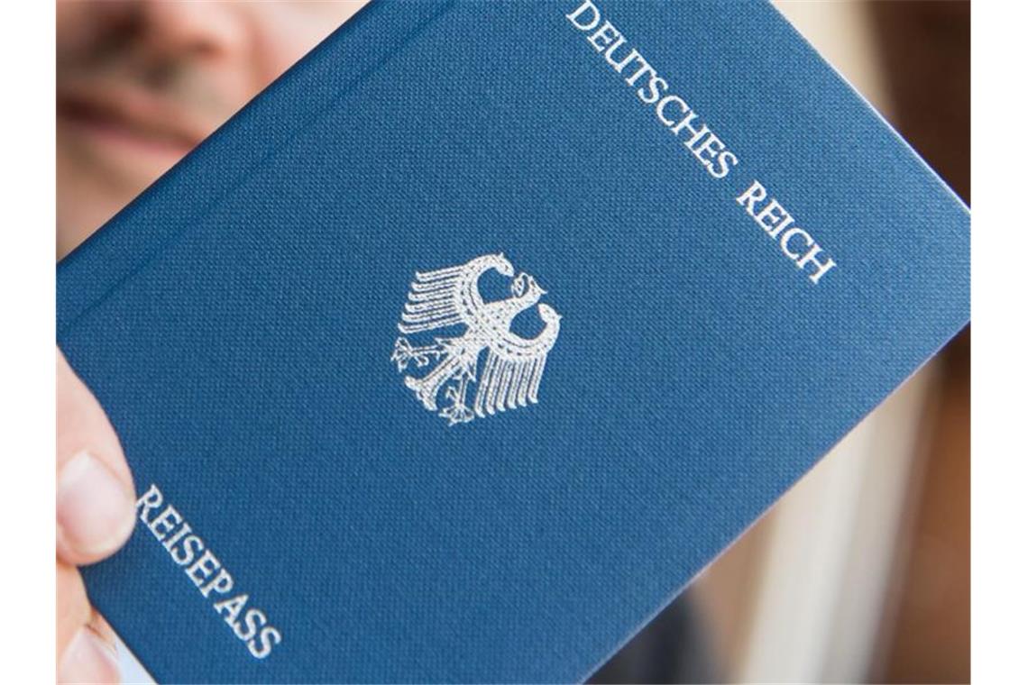 Ein Mann hält einen „Deutsches-Reich-Reisepass“ in der Hand. Foto: Patrick Seeger/dpa