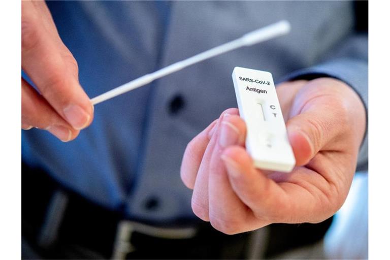 Ein Mann hält einen Schnelltest zur Erkennung des Coronavirus und ein Teststäbchen in den Händen. Foto: Hauke-Christian Dittrich/dpa/Symbolbild