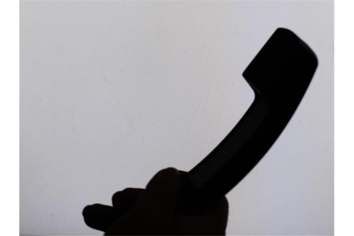 Trickbetrüger bringen Seniorin um mehrere Tausend Euro Ein Mann hält einen Telefonhörer. Foto: Armin Weigel/dpa/Symbolbild