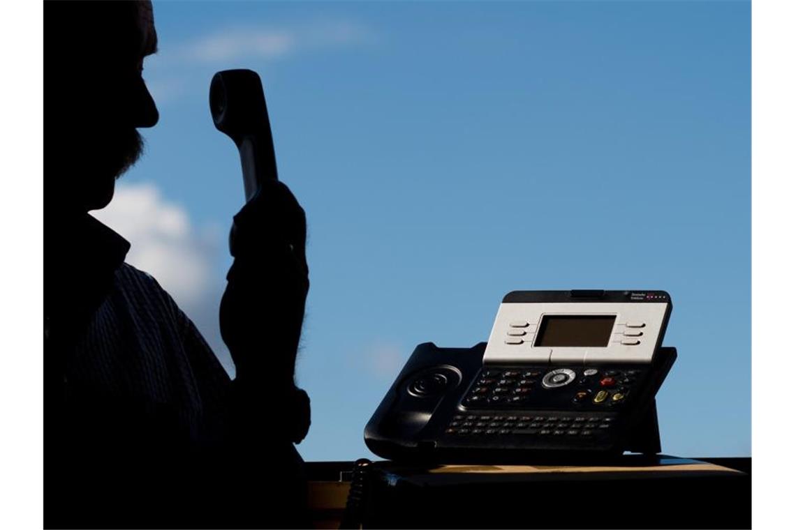 Trickbetrüger bringen älteres Ehepaar um 100 000 Euro Ein Mann hält einen Telefonhörer in der Hand. Foto: Julian Stratenschulte/dpa/Symbolbild