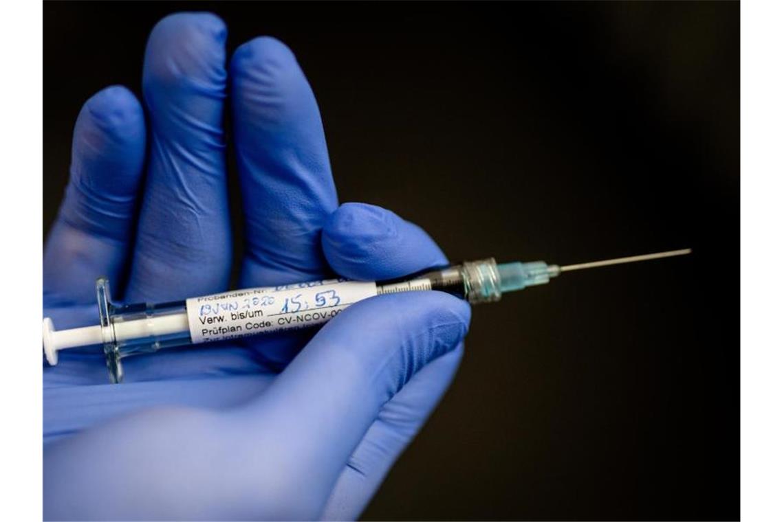 Ein Mann hält im Institut für Tropenmedizin an der Uniklinik Tübingen eine Spritze in der Hand, mit der einer jungen Frau, die erste Probandin, ein möglicher Wirkstoff gegen das Coronavirus gespritzt wurde. Foto: Christoph Schmidt/dpa