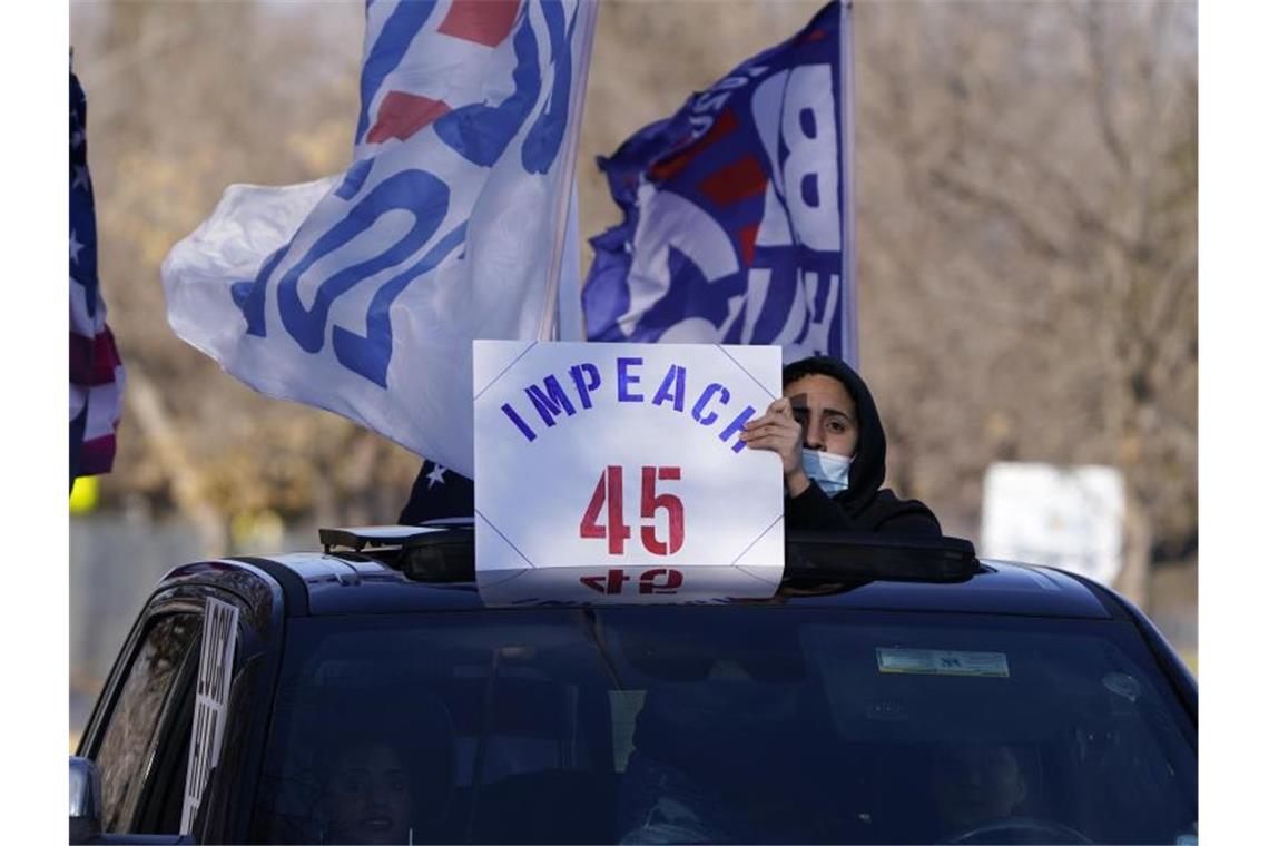 Ein Mann hält in Denver ein Schild aus dem Auto, das die Amtsenthebung von Präsident Donald Trump fordert. Foto: David Zalubowski/AP/dpa