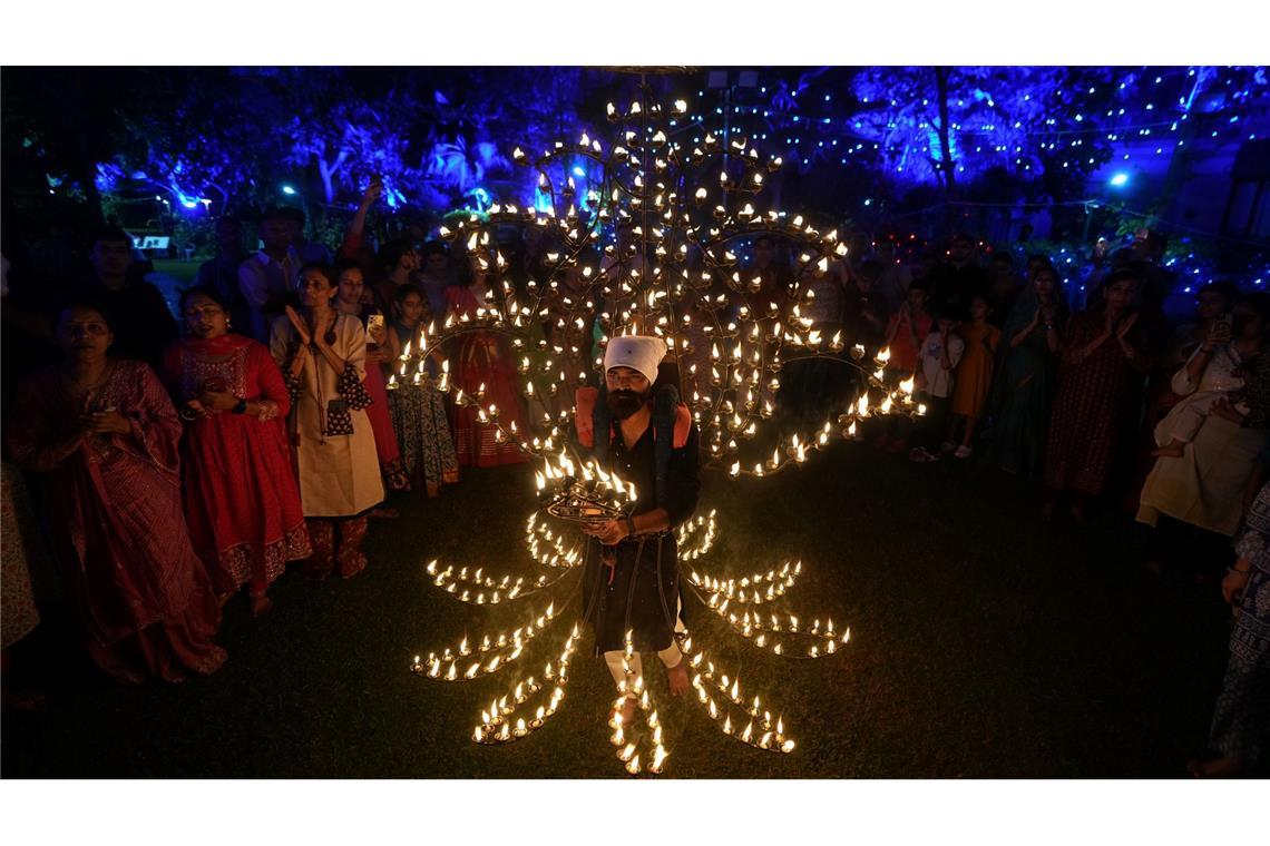 Bilder des Tages Ein Mann hält in einem mit Öllampen geschmückten Kostüm in der fünften Nacht von Navratri, dem Fest der neun Nächte, das Aarti-Ritual ab.
