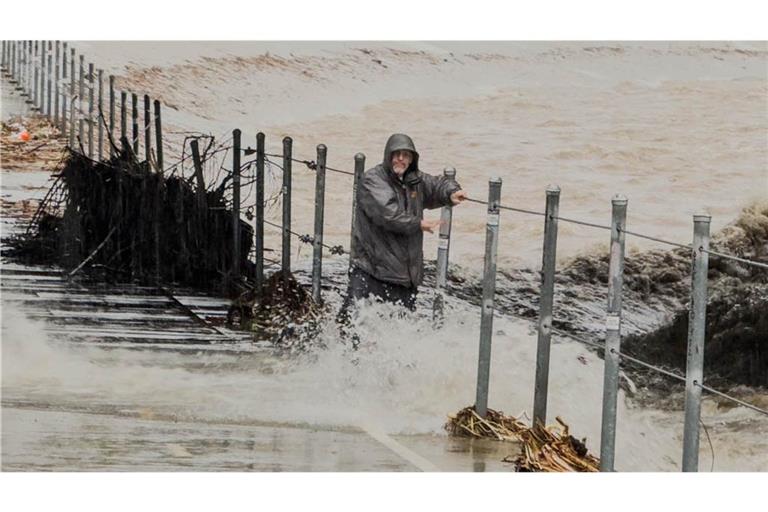 Ein Mann hält sich an einem Geländer fest, nachdem er während eines Sturms an Heiligabend in Glendales in einen reißenden Kanalisationsschacht getreten ist.