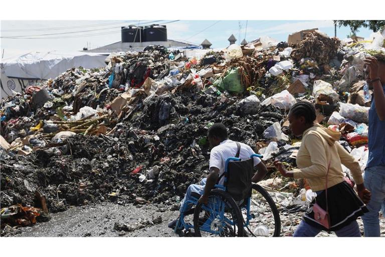 Ein Mann im Rollstuhl versucht, die Straße zu überqueren, vorbei an Müll im Viertel Petion-ville in Port-au-Prince, Haiti.
