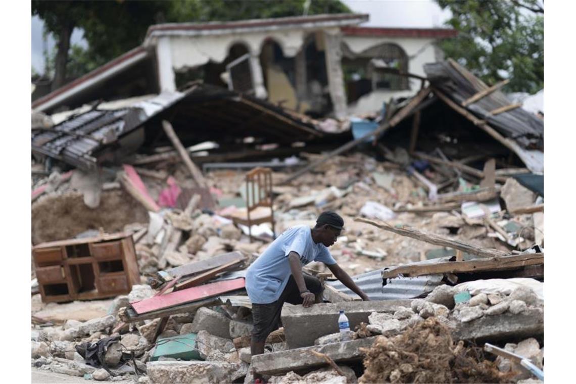 Fast 2000 Tote in Haiti - Überlebenden fehlt Hilfe Ein Mann in den Trümmern eines eingestürzten Hause. Nach dem Erdbeben in Haiti ist die Zahl der bestätigten Todesopfer auf fast 2000 gestiegen. Foto: David de la Paz/XinHua/dpa