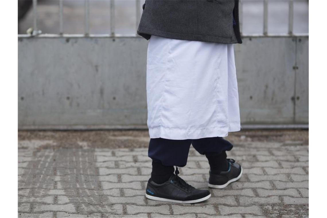 Ein Mann in traditioneller Bekleidung steht vor einem Versammlungsort der Salafisten in Berlin. Foto: Florian Schuh/dpa