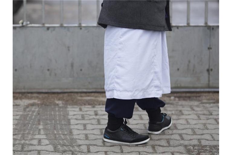 Ein Mann in traditioneller Bekleidung steht vor einem Versammlungsort der Salafisten in Berlin. Foto: Florian Schuh/dpa