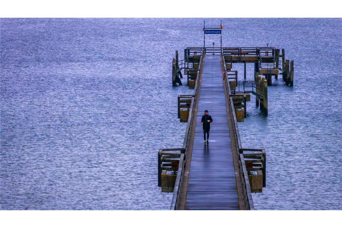 Bilder des Tages Ein Mann joggt bei Regen am frühen Morgen über die Seebrücke am Ostseestrand.