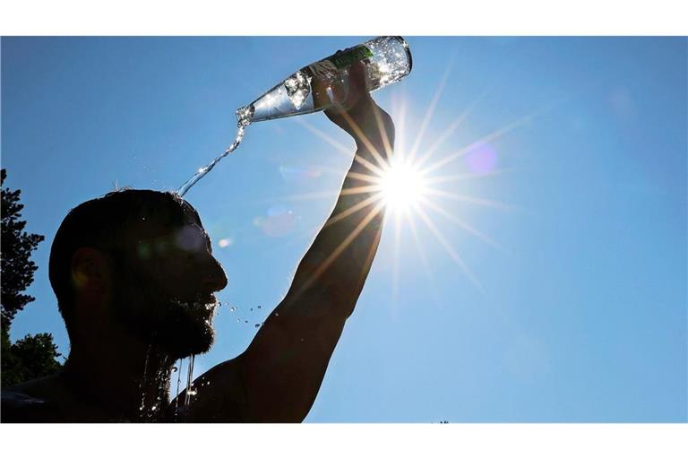 Ein Mann kühlt sich bei sommerlichen Temperaturen ab, in dem er sich eine Flasche mit Wasser über den Kopf schüttet. Am Wochenende wird es heiß (Symbolfoto).