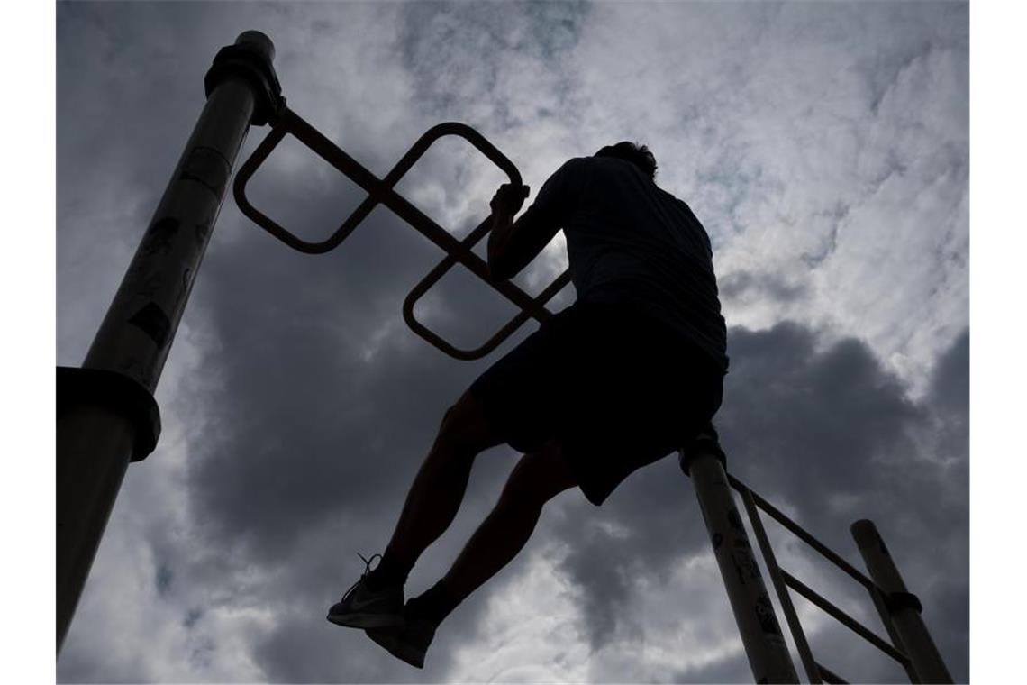 Junge Menschen bewegten sich im zweiten Lockdown weniger Ein Mann macht an einer Gerätestation auf einem Fitnessparcour Klimmzüge. Foto: Sebastian Gollnow/dpa/Archivbild