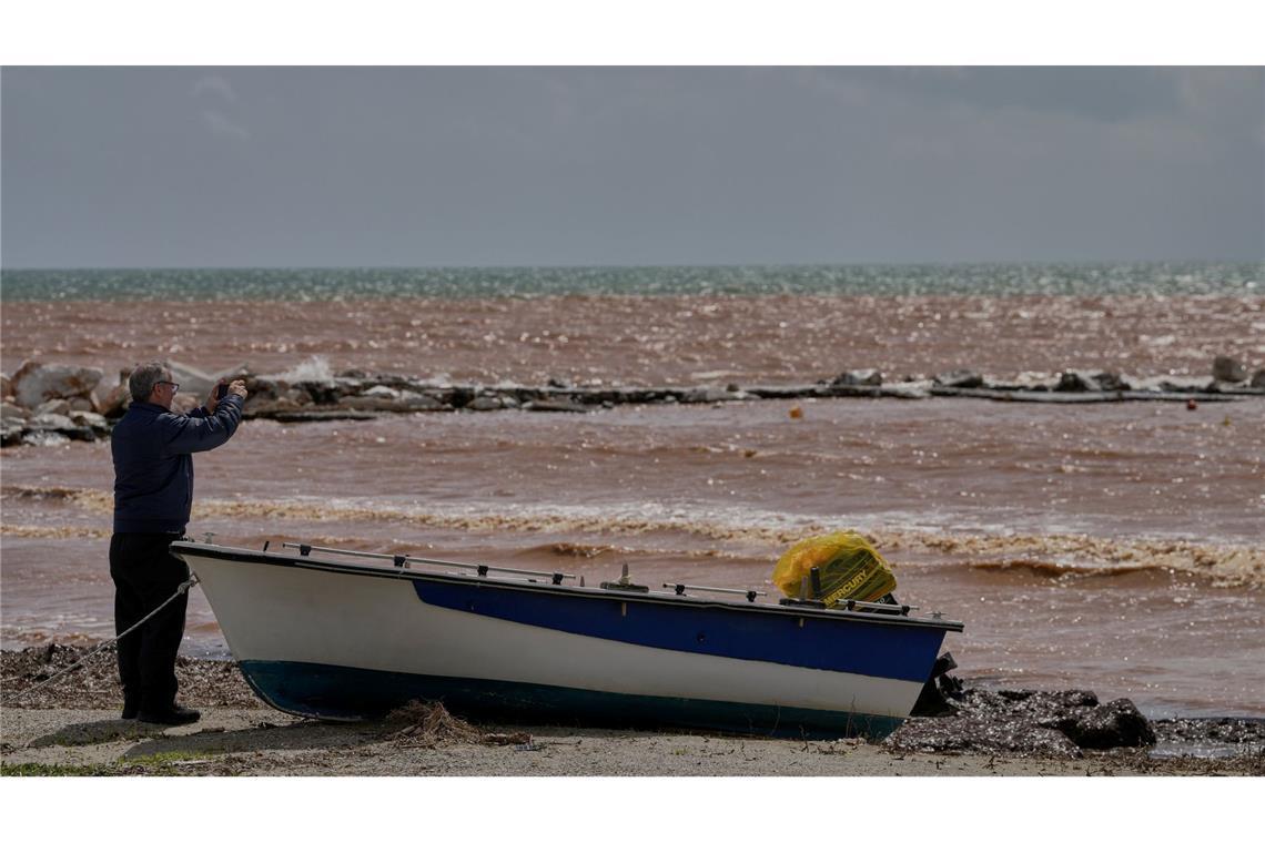 Ein Mann macht Fotos am Strand von Marathon, nachdem schwere Stürme über Nacht große Schäden verursacht haben.