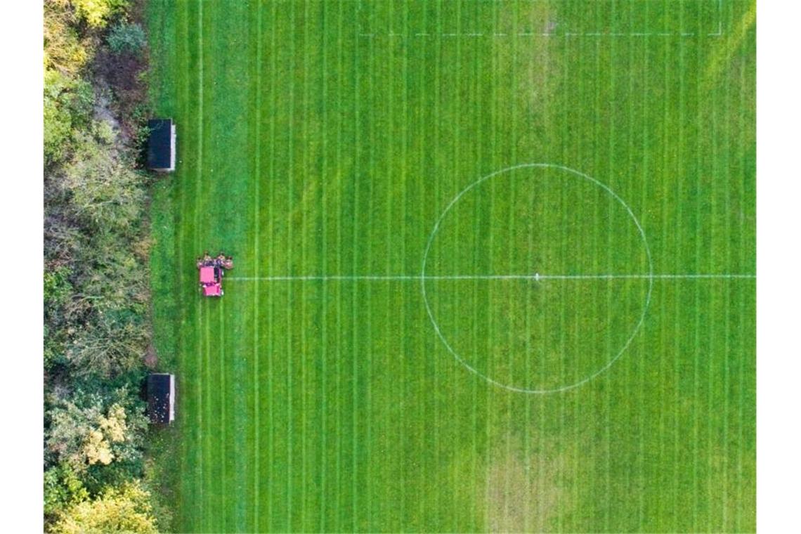 Ein Mann mäht den Rasen eines Fußballplatzes eines Amateurfussballvereins. Foto: Julian Stratenschulte/dpa/Archivbild