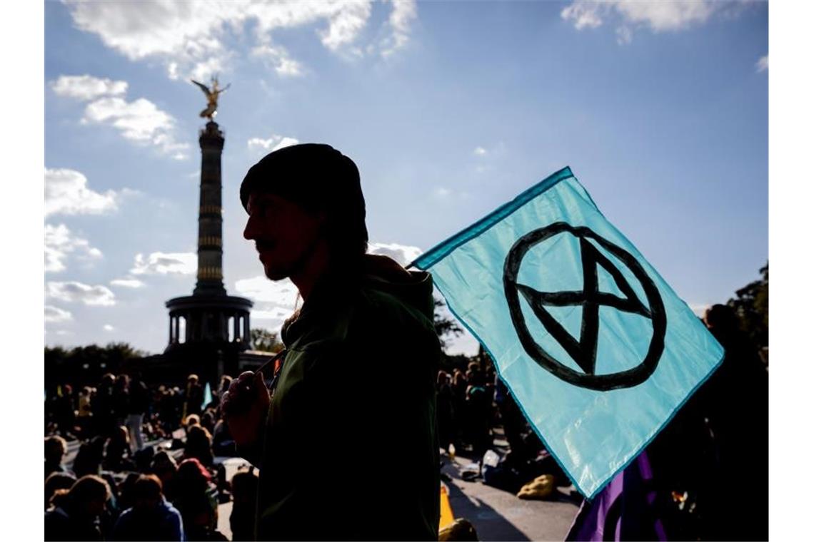 Nach Klima-Blockaden Potsdamer Platz in Berlin geräumt Ein Mann mit einer Extinction-Rebellion-Fahne vor der Siegessäule in Berlin. Foto: Christoph Soeder/dpa